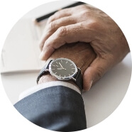 Dwie ręcę mężczyzny skrzyżowane. Na jednej z rąk jest czarny zegarek
