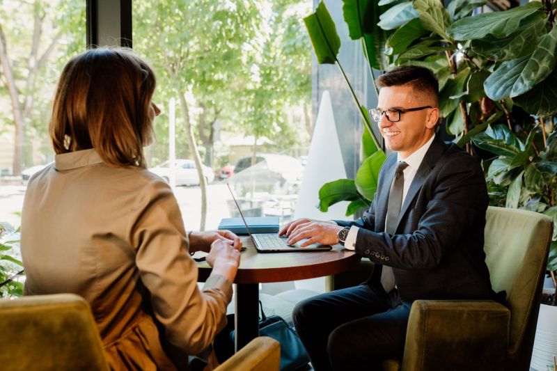 Piotr Grudniewski z klientką na spotkaniu. Siedzą przy stole w kawiarni przy okrągłym stole.